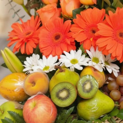 Primer plano extremo de Arreglo Floral con Frutas Hadar, mostrando gerberas naranjas, margaritas blancas, peras, kiwis, manza