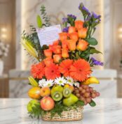 Arreglo floral con rosas naranjas, gerberas, lirios, margaritas y statice morado, combinado con frutas frescas como uvas, kiw