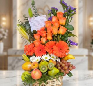 Arreglo floral con rosas naranjas, gerberas, lirios, margaritas y statice morado, combinado con frutas frescas como uvas, kiw