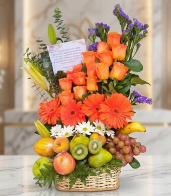 Arreglo floral con rosas naranjas, gerberas, lirios, margaritas y statice morado, combinado con frutas frescas como uvas, kiw
