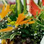 Primer plano extremo de un arreglo floral con frutas Platonia, destacando la textura hiperrealista de las flores, sutiles got