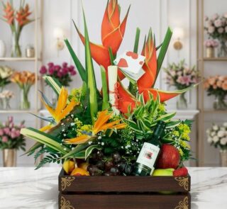Arreglo Floral con Frutas Platonia en una caja de madera, con flores exóticas como aves del paraíso y heliconias, uvas, manza