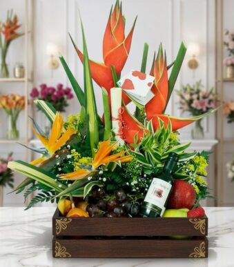 Arreglo Floral con Frutas Platonia en una caja de madera, con flores exóticas como aves del paraíso y heliconias, uvas, manza