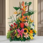 Arreglo floral con frutas exóticas, lirios, girasoles y aves del paraíso sobre mármol, ideal para floristería premium.