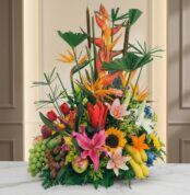 Arreglo floral con frutas exóticas, lirios, girasoles y aves del paraíso sobre mármol, ideal para floristería premium.
