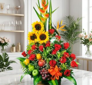 Arreglo floral grande y vibrante con girasoles, rosas rojas, heliconias, aves del paraíso y frutas tropicales frescas como ma