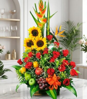 Arreglo floral grande y vibrante con girasoles, rosas rojas, heliconias, aves del paraíso y frutas tropicales frescas como ma