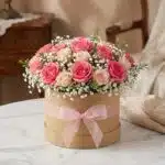 Arreglo floral GIADA con 12 rosas frescas rosadas y crema en una caja redonda de cartón con lazo rosa, ideal para regalo.