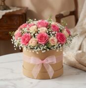 Arreglo floral GIADA con 12 rosas frescas rosadas y crema en una caja redonda de cartón con lazo rosa, ideal para regalo.