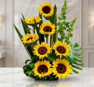 Arreglo floral exótico y grande con girasoles Bengala de pétalos amarillos intensos y centros oscuros, hojas verdes exuberant