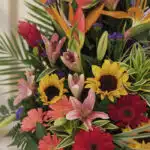 Primer plano extremo del Arreglo Floral IDARA con rosas, girasoles, lirios y aves del paraíso, mostrando texturas hiperrealis