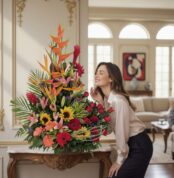 Mujer elegante admirando con deleite el Arreglo Floral IDARA, un diseño exclusivo con rosas y flores exóticas en un lujoso in