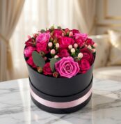 Arreglo floral LILIAN en caja negra con cinta rosa, lleno de rosas lila y rojas, ideal para regalar.