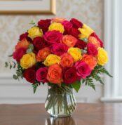 Arreglo floral MARIELLA con 36 rosas frescas en tonos rojo, amarillo, fucsia y naranja, presentado en un elegante jarrón de c