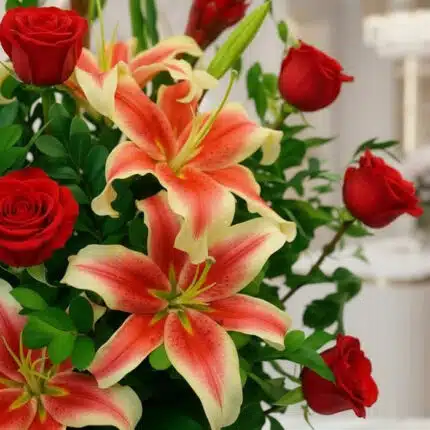 Primer plano extremo de un arreglo floral 'Me Encantas' con lirios bicolores y rosas rojas, mostrando texturas hiperrealistas
