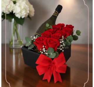 Arreglo floral NATALE con rosas rojas frescas, vino espumoso y lazo rojo en caja negra, ideal para regalo elegante.