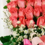 Primer plano extremo de un arreglo floral 'Quiero que Sepas' con rosas rosadas, margaritas blancas y gotas de rocío, destacan