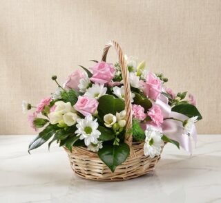 Cesta de mimbre con 12 rosas rosadas, margaritas blancas, freesias y claveles, ideal para regalar en ocasiones especiales.