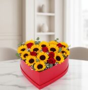 Arreglo floral RINA en forma de corazón con girasoles vibrantes y rosas rojas, ideal para expresar amor y alegría en cualquie