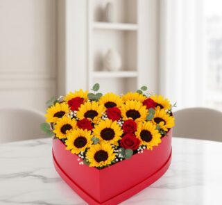 Arreglo floral RINA en forma de corazón con girasoles vibrantes y rosas rojas, ideal para expresar amor y alegría en cualquie