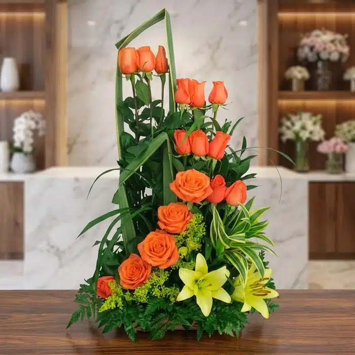 Arreglo Floral Romeo: Exótico y Vibrante con Rosas Naranjas Arreglo Floral Romeo con rosas naranjas abiertas, lirios amarillos y follaje verde exuberante, sobre una superficie de mármol