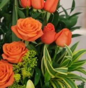 Primer plano extremo de un Arreglo Floral Romeo con rosas naranjas vibrantes, gotas de rocío sutiles y follaje verde, destaca