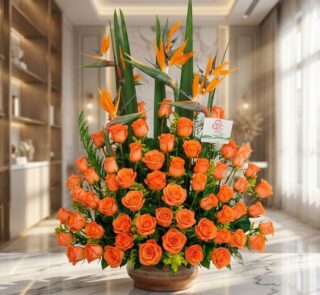 Impresionante arreglo floral exótico con rosas naranjas vibrantes y aves del paraíso, sobre una superficie de mármol en un en