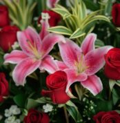 Primer plano extremo de un arreglo floral 'Siempre Juntos' con lirios rosados y rosas rojas, mostrando texturas hiperrealista