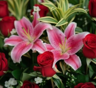 Primer plano extremo de un arreglo floral 'Siempre Juntos' con lirios rosados y rosas rojas, mostrando texturas hiperrealista