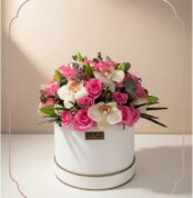 Arreglo floral TANIA con rosas rosadas vibrantes y orquídeas blancas delicadas en una caja redonda blanca con borde dorado, i