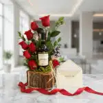 Arreglo floral VERITA con rosas rojas frescas, botella de vino tinto, tarjeta de regalo elegante y cinta satinada roja sobre
