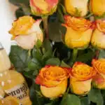 Primer plano extremo de rosas amarillas y naranjas con gotas de rocío, parte del Arreglo Floral Zeus, mostrando textura hiper