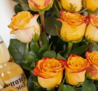 Primer plano extremo de rosas amarillas y naranjas con gotas de rocío, parte del Arreglo Floral Zeus, mostrando textura hiper