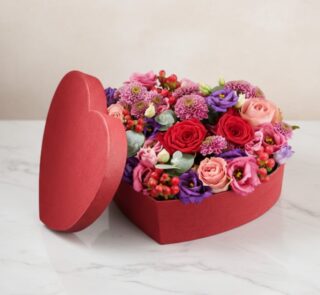 Arreglo floral ZITA en caja de corazón roja con rosas rojas, rosadas y flores mixtas, ideal para regalar en ocasiones especia