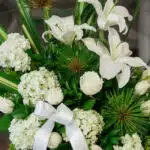 Arreglo fúnebre Adiós Para Siempre con lirios blancos, rosas blancas, hortensias y follaje verde, con rocío sutil y cinta sat