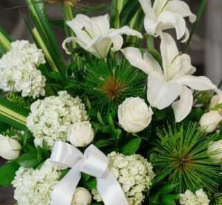 Arreglo fúnebre Adiós Para Siempre con lirios blancos, rosas blancas, hortensias y follaje verde, con rocío sutil y cinta sat