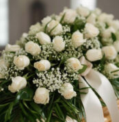 Fotografía macro premium del Arreglo Fúnebre Cubre Caja Cielo, con rosas blancas, follaje verde y rocío sutil. Detalle de cin