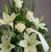 Fotografía macro premium del Arreglo Fúnebre Descanso Eterno, mostrando lirios y rosas blancas con rocío sutil, follaje verde