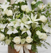 Fotografía macro premium de Arreglo Fúnebre Infinito con lirios y rosas blancas, follaje verde, rocío sutil y cinta satinada.