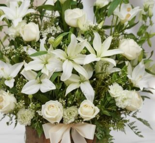 Fotografía macro premium de Arreglo Fúnebre Infinito con lirios y rosas blancas, follaje verde, rocío sutil y cinta satinada.