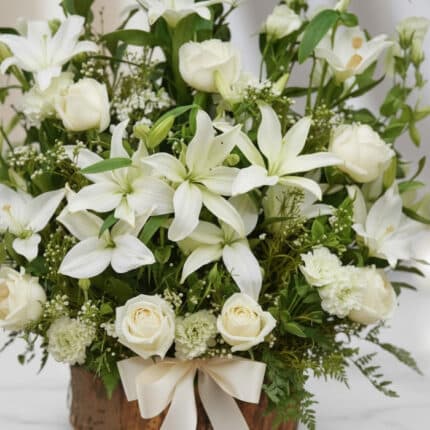 Fotografía macro premium de Arreglo Fúnebre Infinito con lirios y rosas blancas, follaje verde, rocío sutil y cinta satinada.