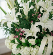 Fotografía macro premium del Arreglo Fúnebre Te Fuiste, mostrando lirios y rosas blancas con rocío sutil, follaje verde y peq