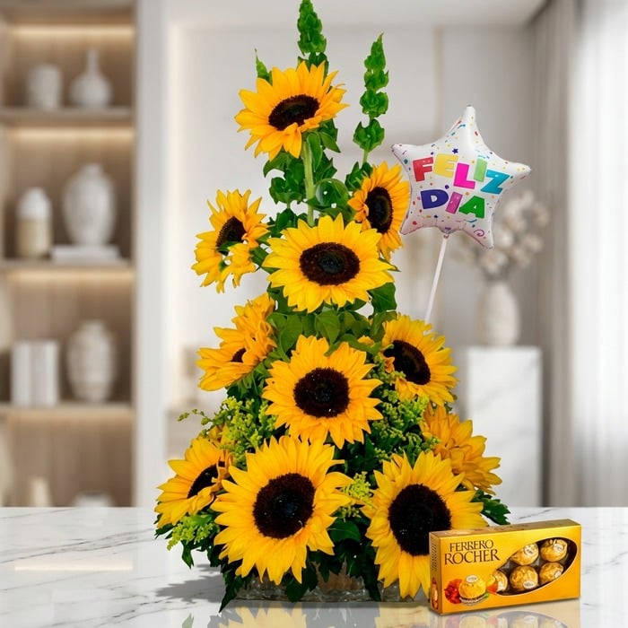 Arreglo floral exótico con girasoles grandes y vibrantes, follaje verde, un globo de 'Feliz Día' y una caja de chocolates Fer