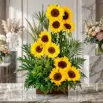 Arreglo floral exótico y grande con girasoles vibrantes y hojas verdes exuberantes, presentado en un estudio premium sobre má