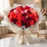 Impresionante bouquet de 72 rosas FILIPPA en tonos rojos, naranjas y rosas, con empaque coreano elegante, sobre mesa de mármo