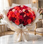 Impresionante bouquet de 72 rosas FILIPPA en tonos rojos, naranjas y rosas, con empaque coreano elegante, sobre mesa de mármo