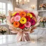 Bouquet Floral Adela, un ramo grande y vibrante de gerberas en tonos rojos, naranjas, amarillos y rosas, con empaque coreano