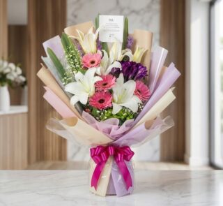 Bouquet de Flores GIA con gerberas rosadas, lirios blancos y flores moradas, envuelto en papel coreano elegante y lazo fucsia