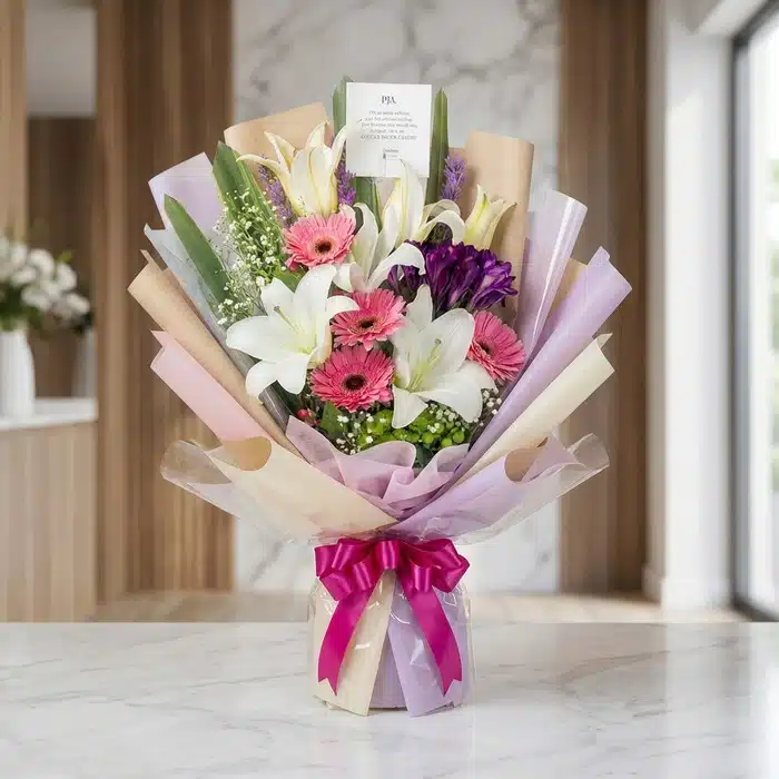 Bouquet de Flores GIA: Gerberas Rosadas, Lirios y Flores Moradas Bouquet de Flores GIA con gerberas rosadas, lirios blancos y flores moradas, envuelto en papel coreano elegante y lazo fucsia