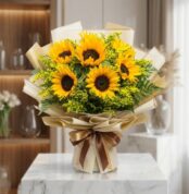 Bouquet de Girasoles LAIA con 10 flores frescas y radiantes, envuelto en papel coreano elegante y lazo marrón, sobre mármol b